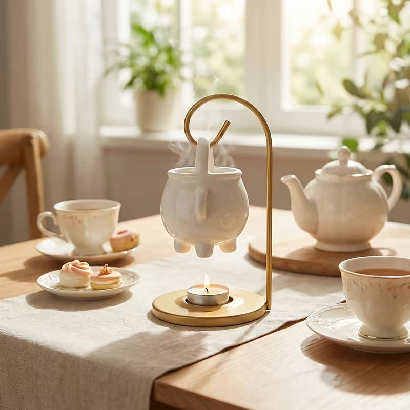Tea-making setup with a teapot, cups, and a small lamp on a table with a window in the background.